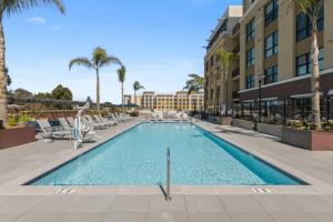 a swimming pool at a resort with chairs and palm trees at Blueground Hayward pool outdoor kitchens SFO-1695 in Hayward