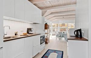 オテルプにあるAmazing Home In Otterup With Wifiの白いキャビネット、シンク、テーブル付きのキッチンが備わります。