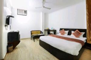 een slaapkamer met een groot bed en een televisie bij Hotel First by Goyal Hoteliers in Agra
