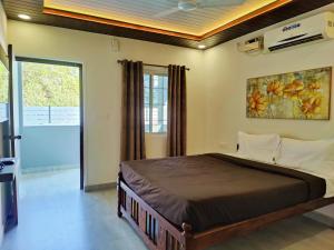 een slaapkamer met een bed met een schilderij aan de muur bij Kevin's House by TravelKrafts in Anjuna