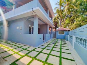 een huis met blauwe muren en groen gras bij Kevin's House by TravelKrafts in Anjuna