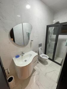 uma casa de banho com um lavatório, um WC e um espelho. em Appartement 2 chambres balcon ABA em Dakar