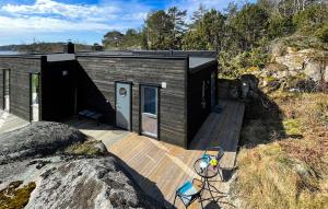 a small house on a wooden deck next to the ocean at Cozy Home In Skjrhalden With House A Panoramic View in Skjærhollen