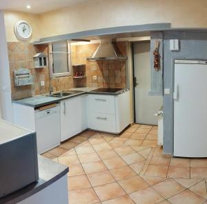 a kitchen with white cabinets and a tile floor at Le Petit Caboulot en pleine nature in Vaumeilh