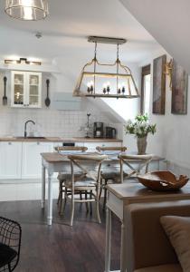 kuchnia z białymi szafkami oraz stołem i krzesłami w obiekcie Mały Domek w Kołobrzegu