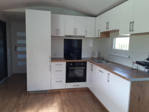 a kitchen with white cabinets and a black appliance at Letnisko Skarpa in Giżycko