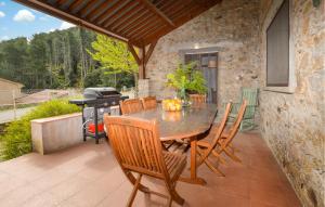 una mesa de madera y sillas en un patio con parrilla en 2 Bedroom Beautiful Home In Popolasca, 