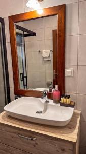een wastafel in de badkamer met een grote spiegel erboven bij Cunda Nesos Pansiyon in Ayvalık