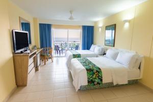 a hotel room with two beds and a flat screen tv at GHL Relax Hotel Costa Azul in Santa Marta