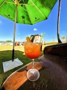 una bebida sentada en una mesa de madera bajo una sombrilla en Apartamento amplo de frente para o mar em Resort, en Entre Rios