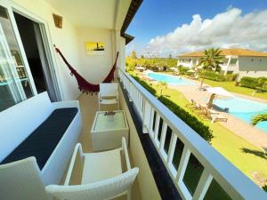 balcón con sillas blancas y piscina en Apartamento amplo de frente para o mar em Resort, en Entre Rios