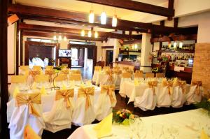 a banquet hall with white tables and chairs with bows at Pensiunea Valea Ursului in Bascov