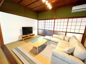 a living room with a couch and a tv at NEW OPEN！田舎の一棟貸住宅、お庭でBBQやプール遊びができる宿。限定５組オープン特別価格！ in Fukuchiyama