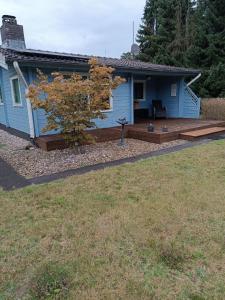 een blauw huis met een houten terras ervoor bij Ferienhaus für 4 Personen ca 56 qm in Winsen-Meissendorf, Lüneburger Heide Südheide in Winsen