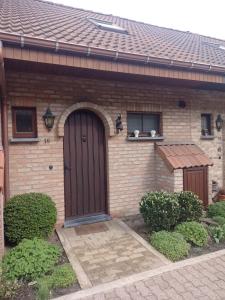 a house with a brown door and two cats on a ledge at Golfbreker in De Haan