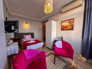 1 dormitorio con sillas rosas, 1 cama y lámpara de araña en Cunda Nesos Pansiyon, en Ayvalık