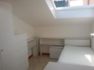 um quarto branco com uma cama e uma janela em Mansarda luminosissima em Pesaro