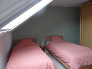 two beds with pink sheets in a room with a skylight at Golfbreker in De Haan