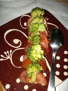 um prato com brócolos e tomates e uma colher em Casa La Union em Castrojeriz