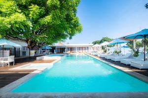 a pool with lounge chairs and umbrellas at a resort at AMP Beach House in Nusa Penida
