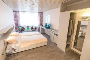 a bedroom with a bed and a desk and a television at Hotel Cronberger Hof in Ladenburg