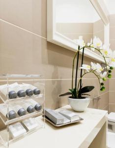 un bagno con bancone bianco e vaso di fiori di Lis Apartment a Milano