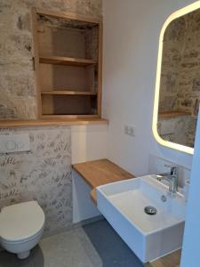 a bathroom with a sink and a toilet and a mirror at Maison de la Plume in Cajarc