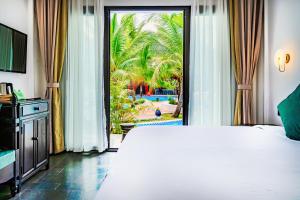 a bedroom with a large bed and a sliding glass door at Manyo Hotel and Resort in Luang Prabang