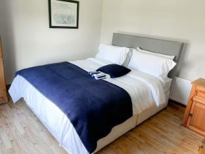 un grande letto con coperta blu e cuscini bianchi di Lisheenbawn Farmhouse Farranfore a Farranfore
