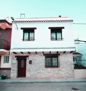 un edificio blanco con 4 ventanas y una puerta roja en La Fragua de la Villa, 