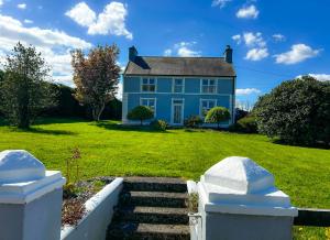 a blue house on a green yard with stairs at Lisheenbawn Farmhouse Farranfore in Farranfore