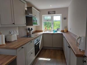 a kitchen with white cabinets and a wooden counter top at Sunnydale, Cartmel in Cartmel