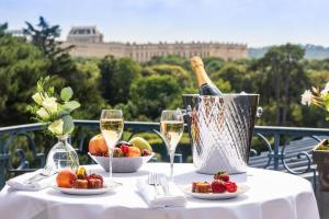 a table with a bottle of wine and a basket of fruit at Waldorf Astoria Versailles - Trianon Palace in Versailles
