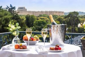 Waldorf Astoria Versailles - Trianon Palace في فرساي: طاولة مع زجاجة من النبيذ وسلة من الفواكه