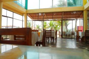 un comedor con mesas, sillas y ventanas en Hotel Canoa´s Wonderland, en Canoa