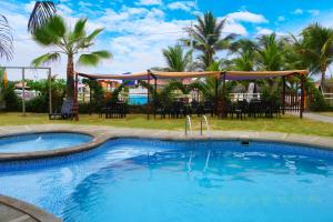 una piscina con tavolo, sedie e palme di Hotel Canoa´s Wonderland a Canoa