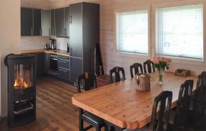 a kitchen with a wooden table and a fireplace at Stunning Home In Bvgen With House Sea View in Bøvågen
