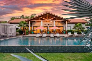 a pool with chairs and umbrellas in front of a building at LAS HOTEL BOUTIQUE in Foz do Iguaçu