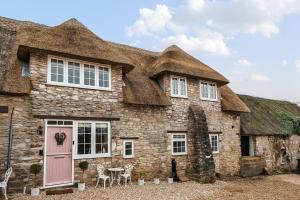 ein altes Steinhaus mit einem Strohdach in der Unterkunft Live the coastal cottage dream in Dorset AONB in Weymouth