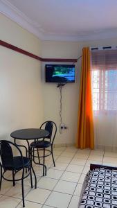 a room with a table and chairs and a tv at Studio room entebbe in Entebbe