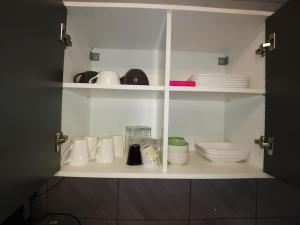 a white cabinet with cups and plates and a toilet at n1 F2 40m2 avec petit jardin in Hérouville-Saint-Clair