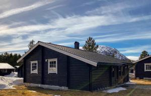 una pequeña casa negra con una montaña cubierta de nieve detrás de ella en 2 Bedroom Lovely Home In Bjorli, en Bjorli