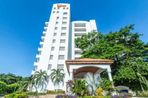 un edificio alto y blanco con un cenador frente a él en GHL Relax Hotel Costa Azul, en Santa Marta