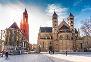 duży budynek z dwoma wieżami i ludźmi stojącymi na zewnątrz w obiekcie Amrâth Hotel DuCasque w mieście Maastricht