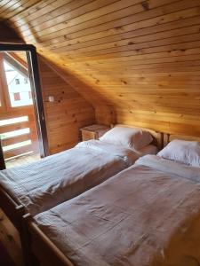 2 Betten in einem Zimmer mit Holzdecke in der Unterkunft Vila Baco in Žabljak