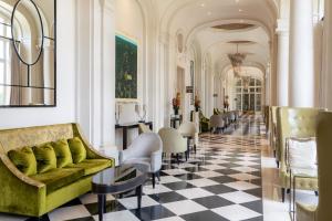 vestíbulo con sofá verde y suelo de tablero de ajedrez en Waldorf Astoria Versailles - Trianon Palace en Versailles