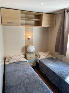 two beds in a small room withermottermottermottermott at Maison mobilhome sans vis à vis au calme et en hauteur in Lège-Cap-Ferret