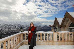 a woman standing on a balcony in the snow at Samar Resort in Bcharré