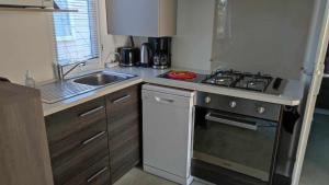a small kitchen with a stove and a sink at Le Daniela Camping Les Sables du midi 4 etoiles in Valras-Plage