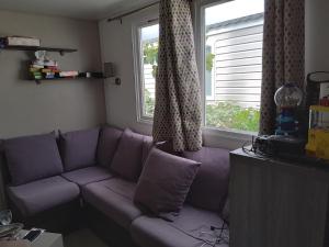 a purple couch in a living room with a window at Le Daniela Camping Les Sables du midi 4 etoiles in Valras-Plage